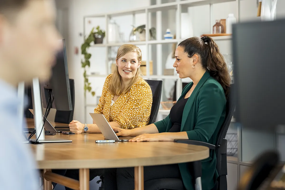 Een groep vrouwen voert een levendige discussie aan een tafel, perfect vastgelegd in deze bedrijfsfotografie.